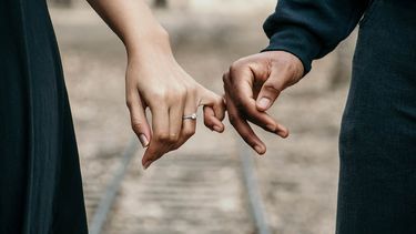 twee handen die elkaars pink vasthouden en in een relatie zijn