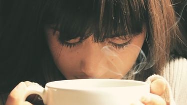 Vrouw die aan een kop koffie ruikt en wil afvallen