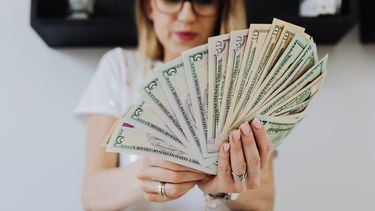 Vrouw die geld telt om te kijken hoeveel ze nog moet sparen voor haar pensioen