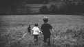gezin met eerste, tweede en derde kind, rennen door een veld
