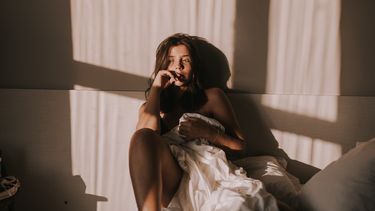 Vrouw die verdrietig in bed zit omdat ze slechte seks heeft door de stress