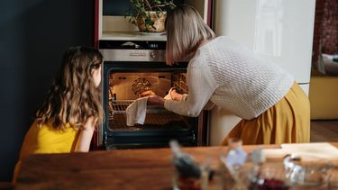 Moeder en dochter die iets uit de oven halen na het bakken voor de Sint