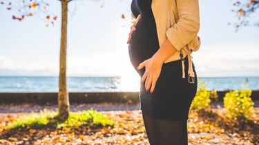 Vrouw die buiten staat en haar zwangere buik laat zien omdat ze HELLP-syndroom heeft