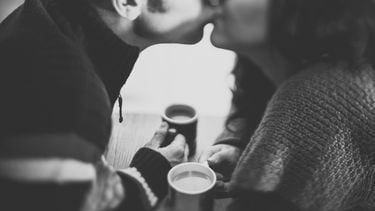 relatie / koppel drinkt koffie en kust elkaar