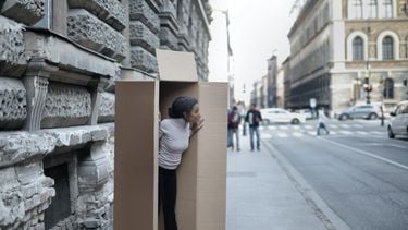 Vrouw staat verstopt in een kartonnen doos op straat alsof ze een introvert is