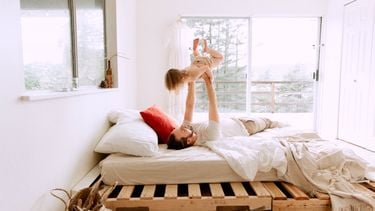 middagslaapje peuter / vader speelt met kind op bed