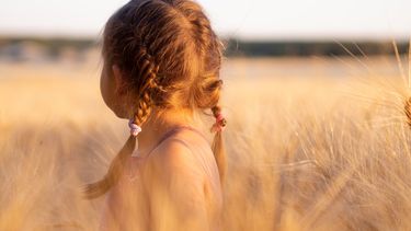 klein meisje staat in een veld