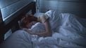 Vrouw die in bed ligt en gek wordt van de jeuk tijdens de zwangerschap