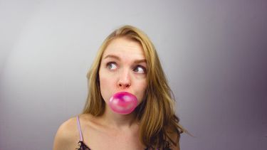Vrouw die kauwgumbel blaast en niet weet dat dat voor een slechte adem zorgt